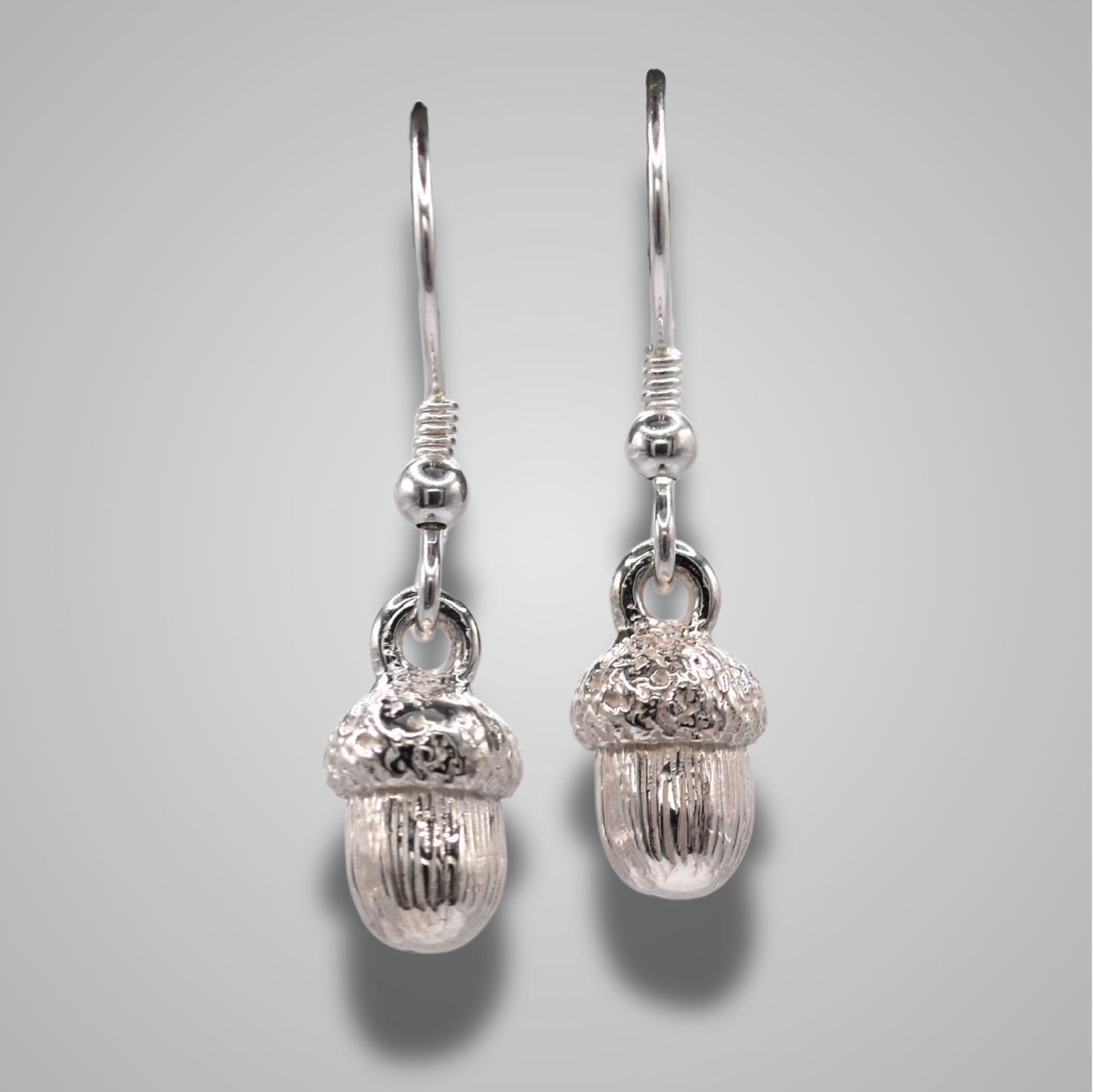 Sterling silver acorn drop earrings on hooks. Intricate details with a shiny polished finish.