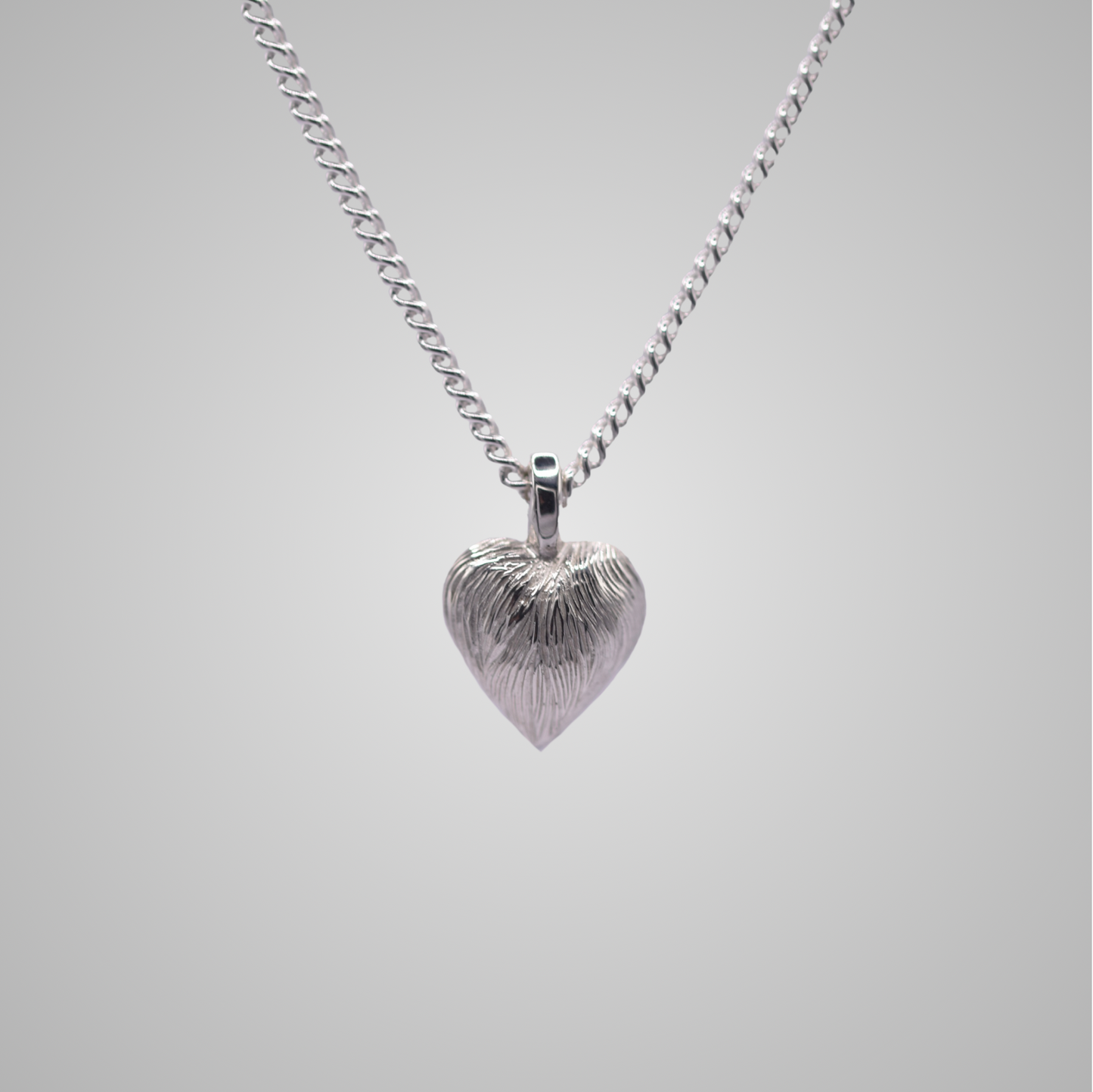 Silver heart pendant on silver chain with shiny engraved flowing lines