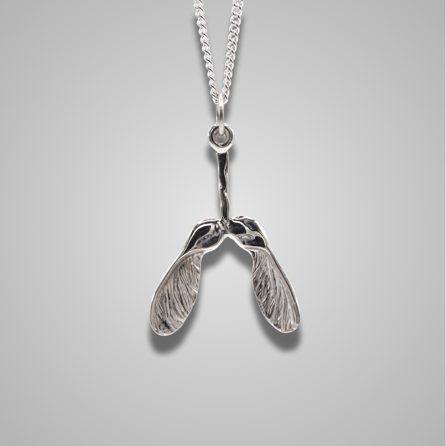 An elegant, and detailed shiny silver sycamore seed with sparky engraving details. A charming pendant.
