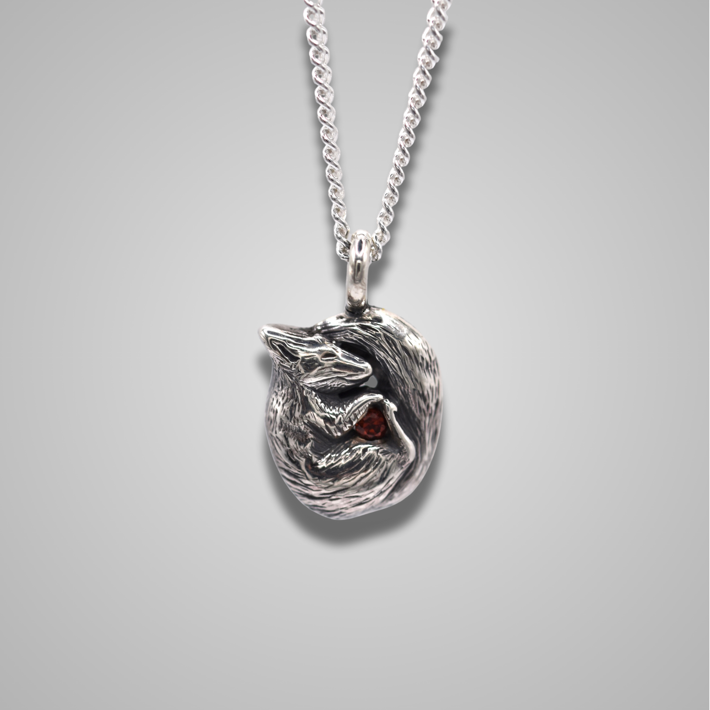 A curled up squirrel snuggling a gemstone. The squirrel is realistic and detailed. The sparkly stone is a red garnet.