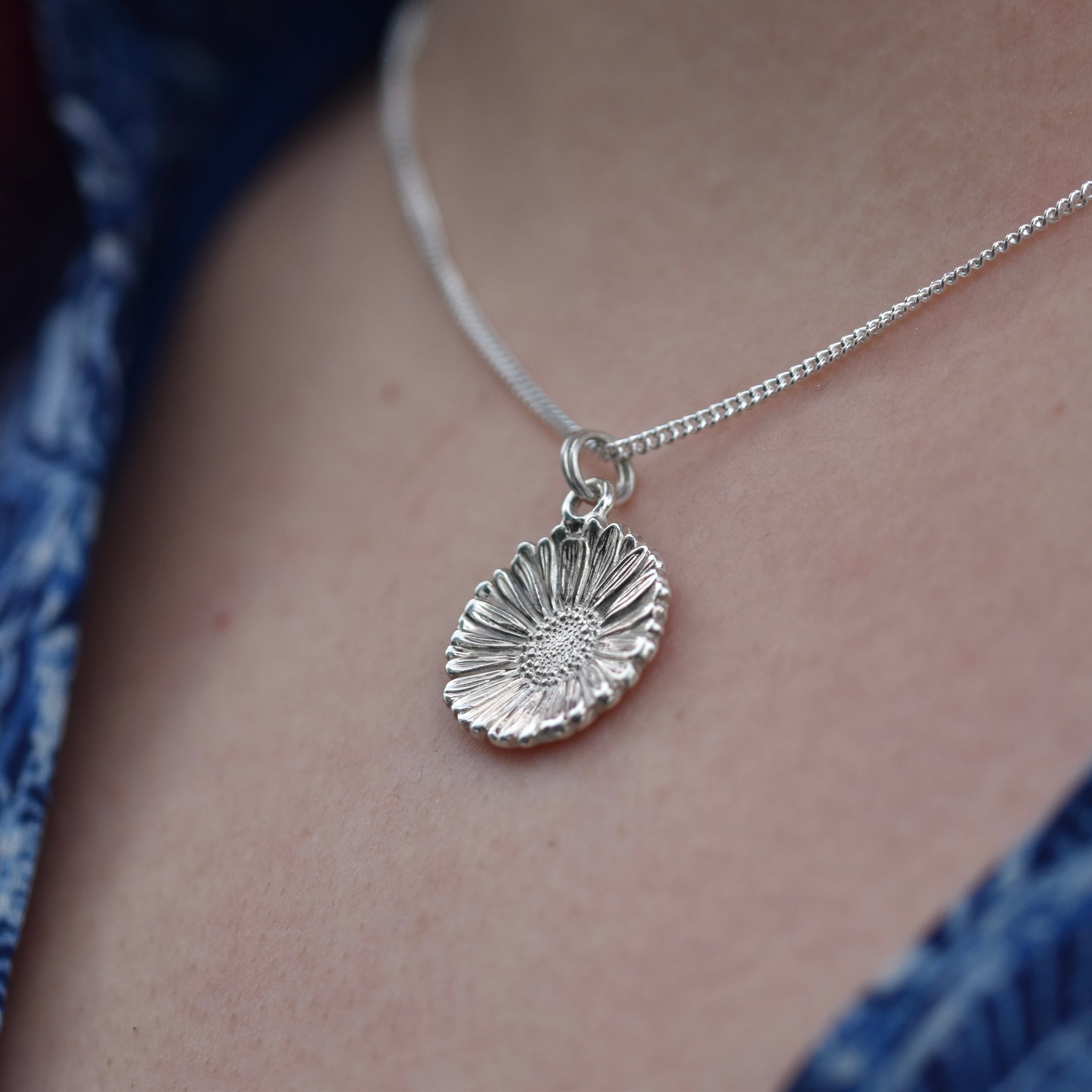 A very detailed and shiny silver Daisy hangs from a silver chain. Very realistic Daisy 