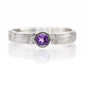 Silver ring with a purple gemstone on a white background