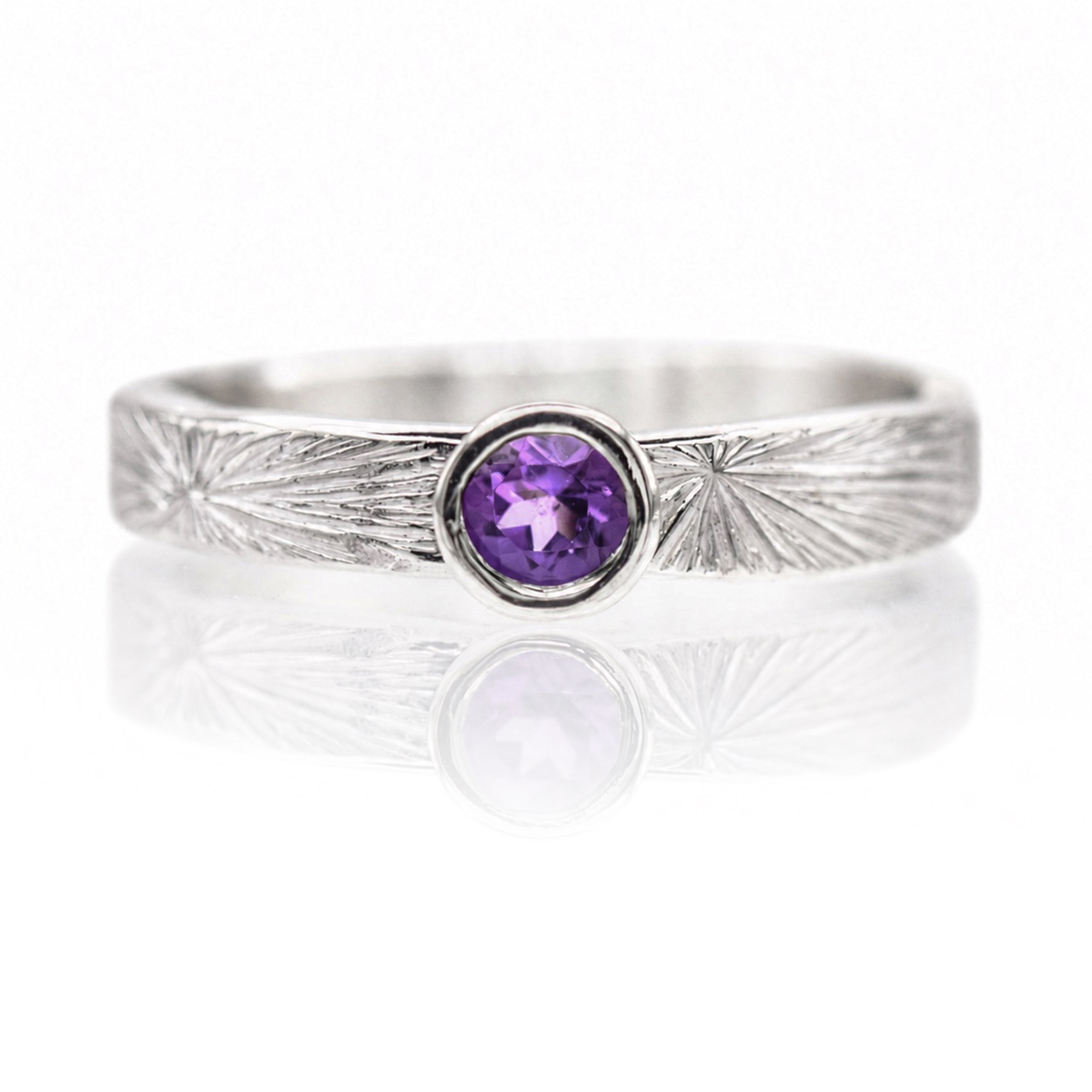 Silver ring with a purple gemstone on a white background