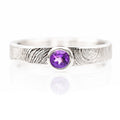 Silver ring with a purple gemstone on a white background