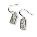 Pair of silver earrings with intricate designs of art nouveau bluebell on a white background