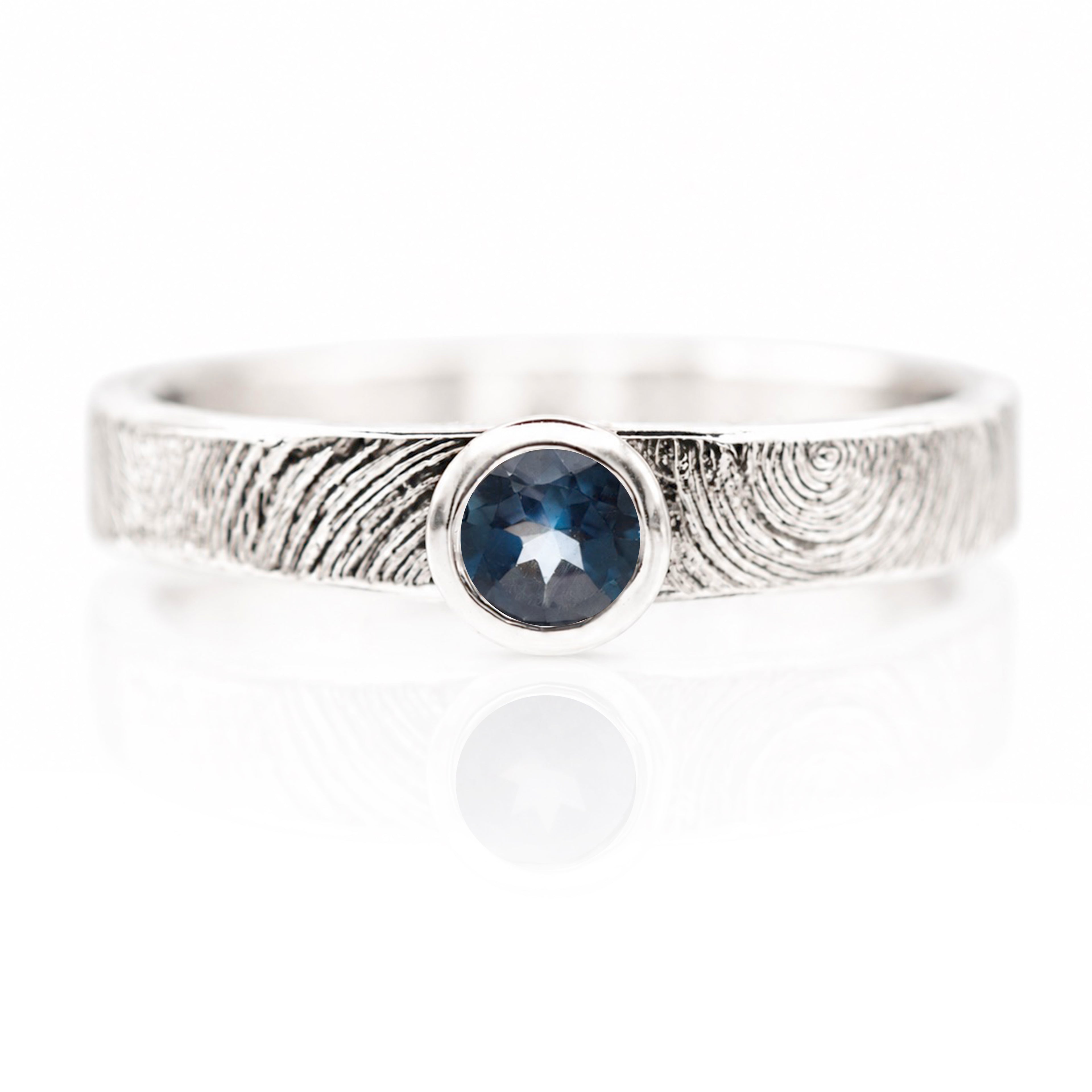 Silver ring with a blue gemstone on a white background