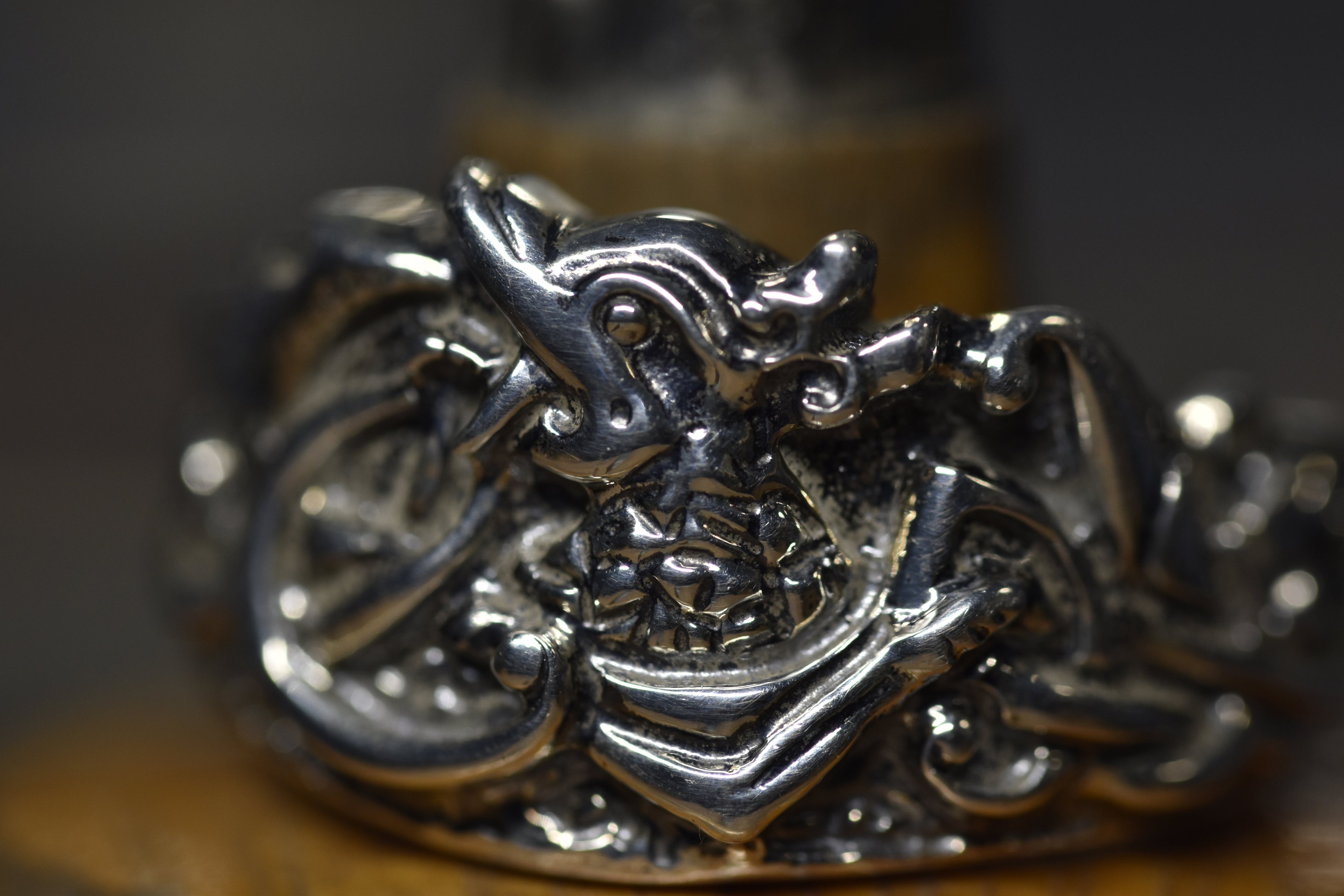 Close-up of a silver ring with intricate design  of the maeshowe dragon on a blurred background