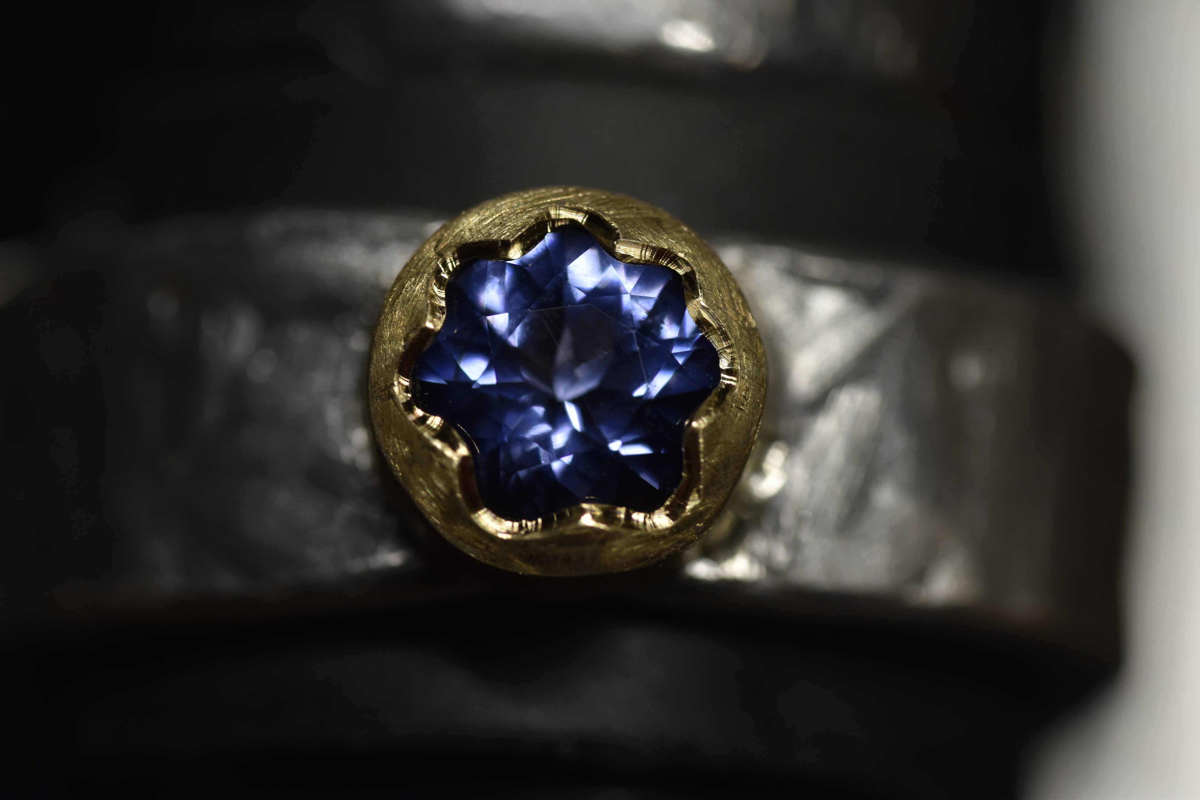Close-up of a gold ring with a blue gemstone on a dark background