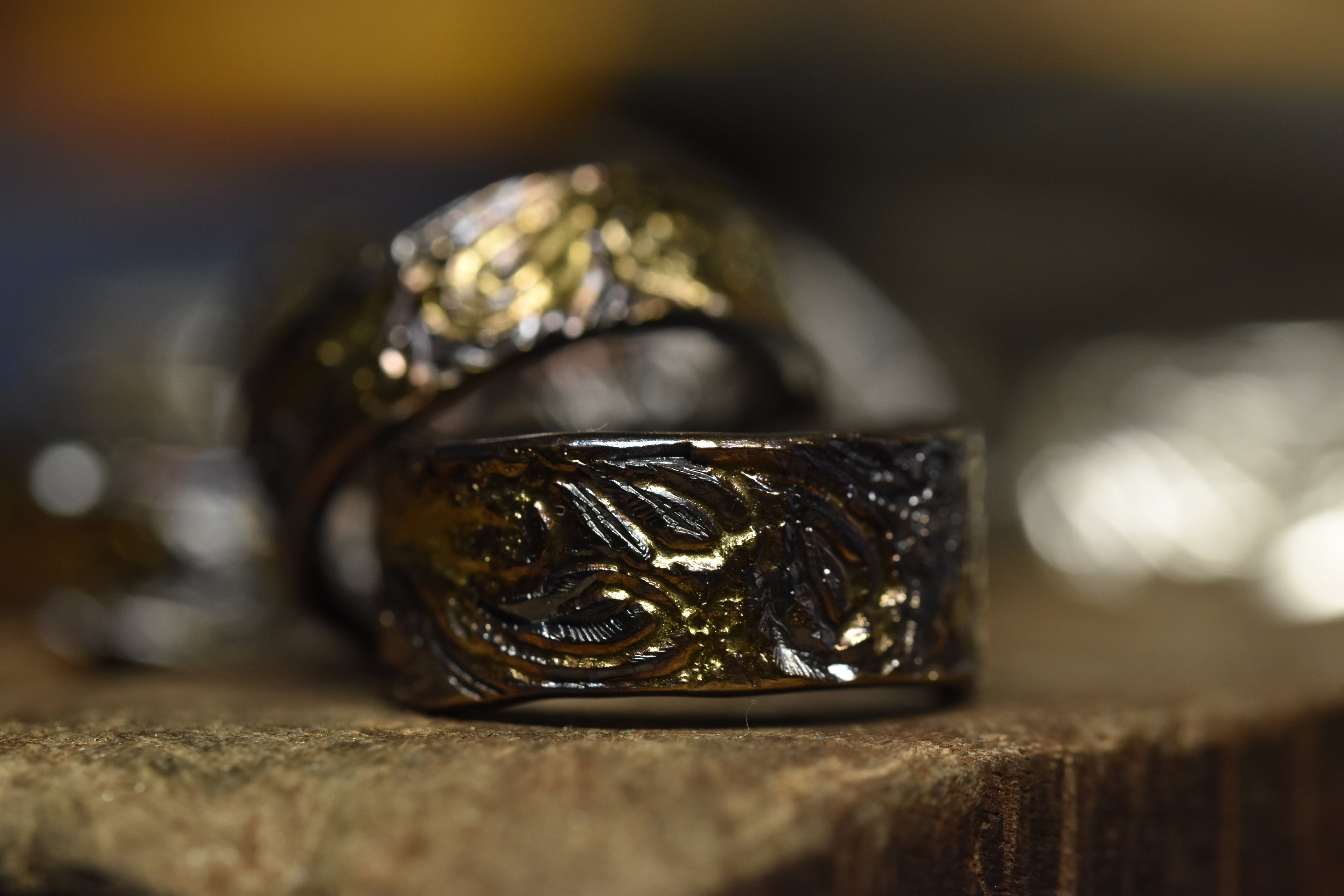 Close-up of two ornate rings on a wooden surface with a blurred background