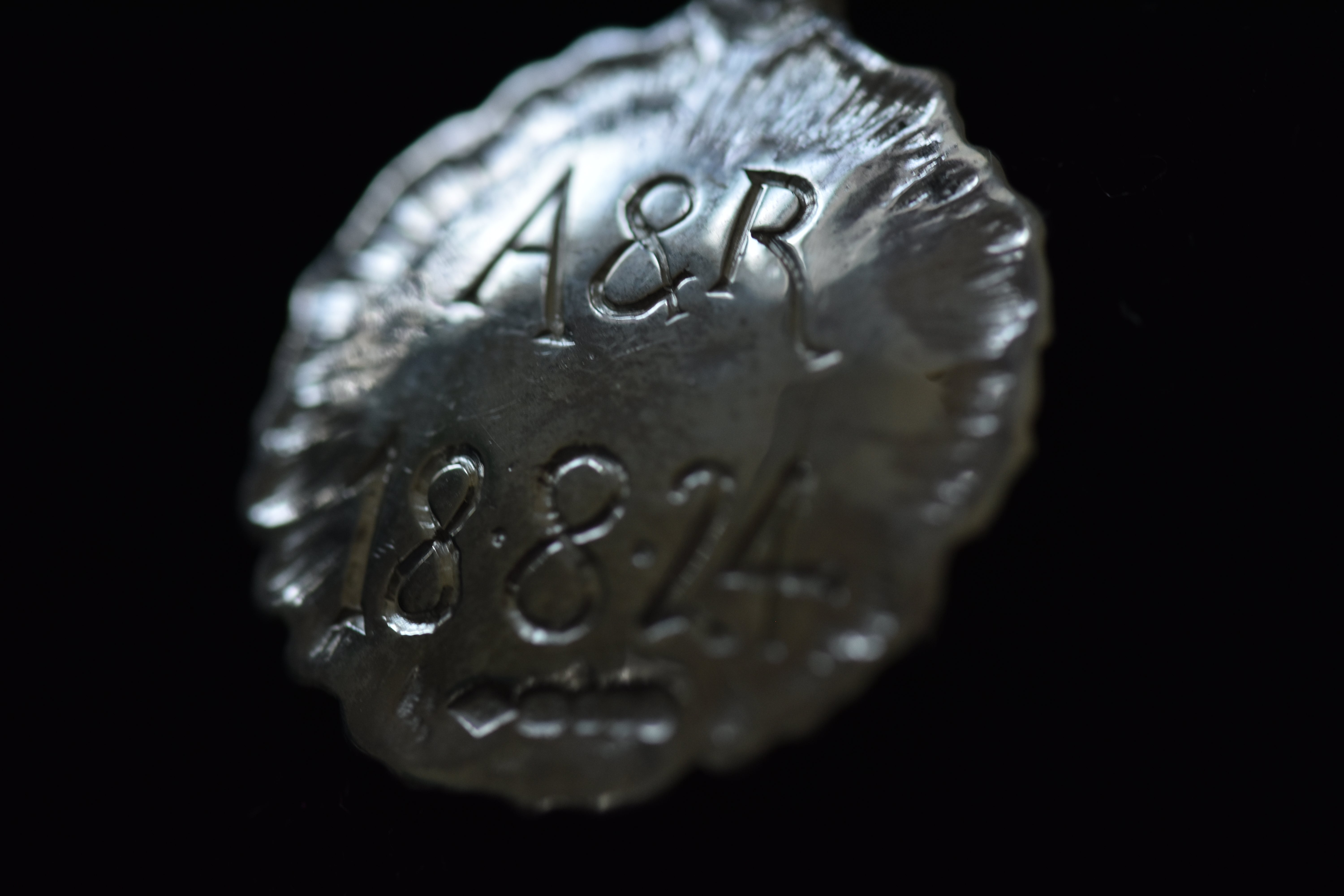 Silver pendant with hand engraved lettering reading A&R 18.8.24