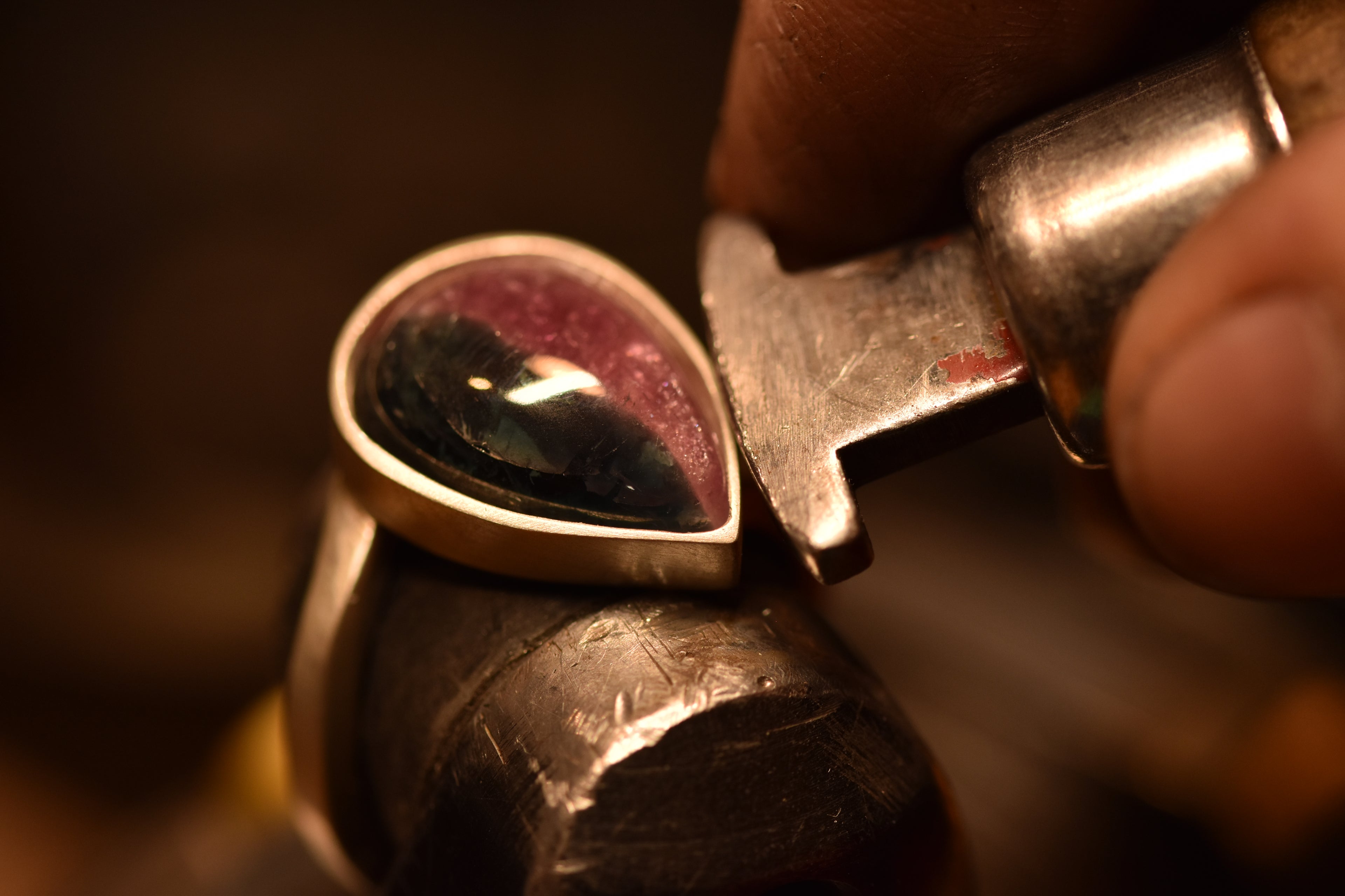 close up of hands setting a pearshaped stone