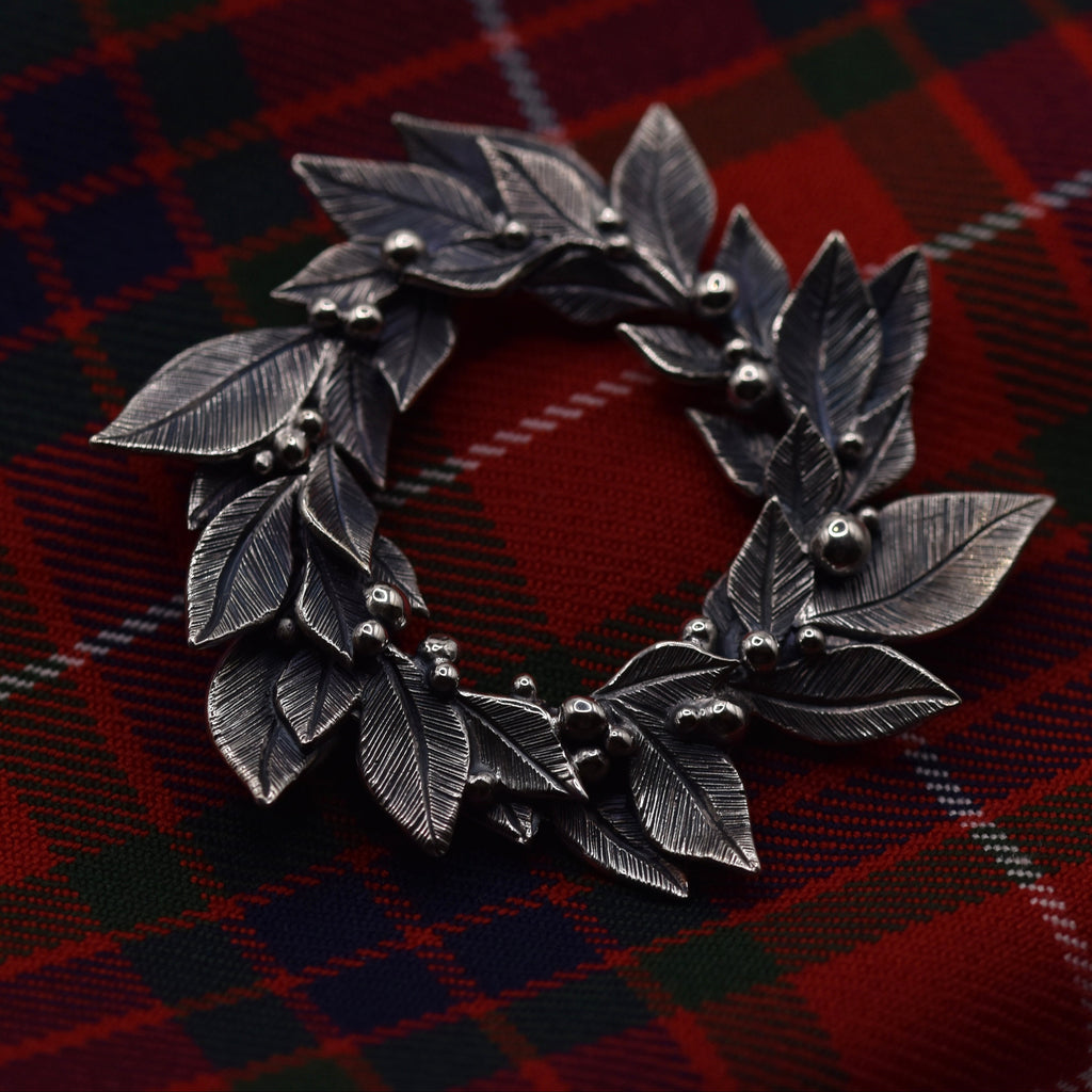 Silver leaf-shaped brooch on a red plaid fabric background
