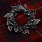 Silver leaf-shaped brooch on a red plaid fabric background