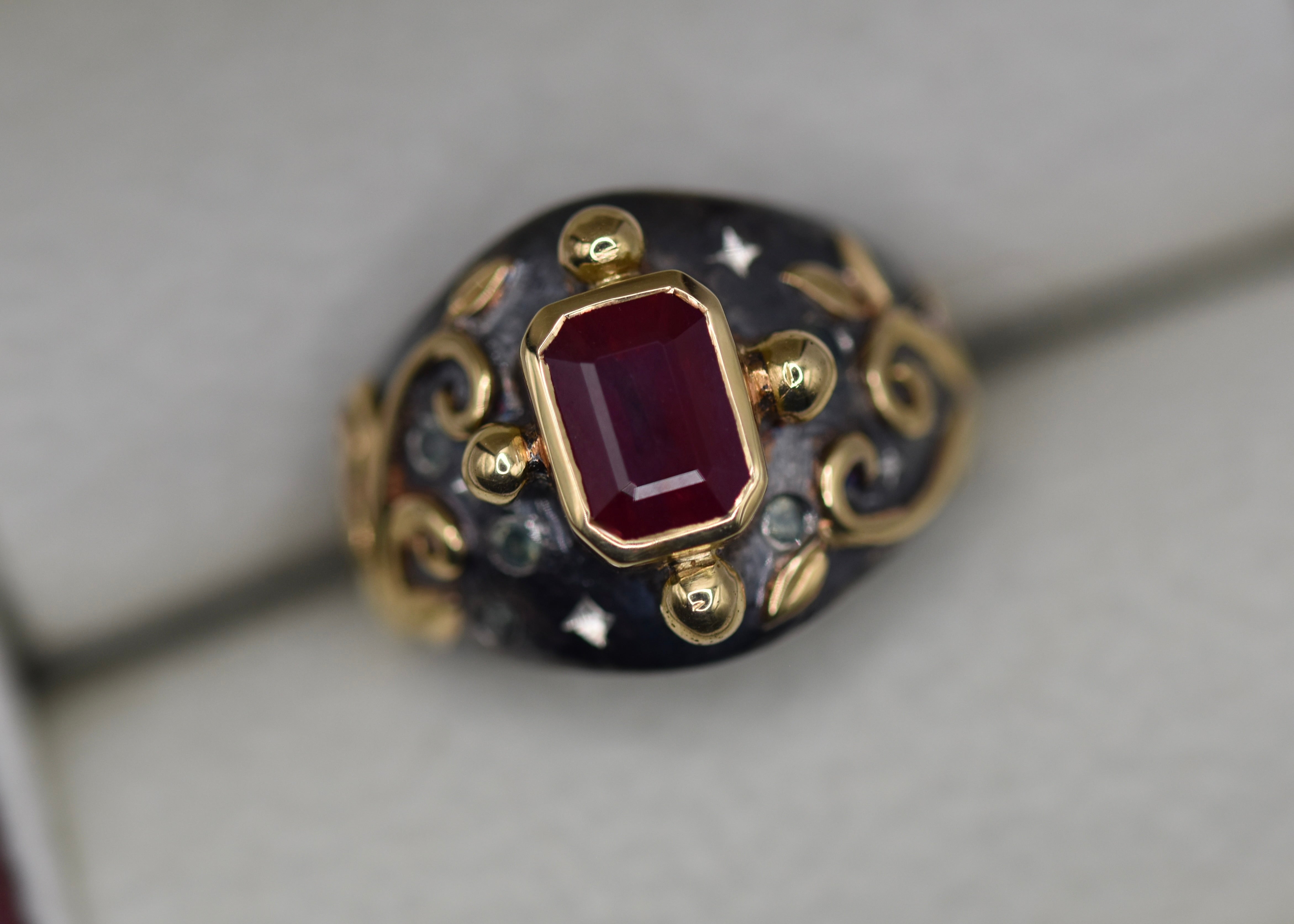 Gold ring with a ruby gemstone on a gray background with bright cut stars