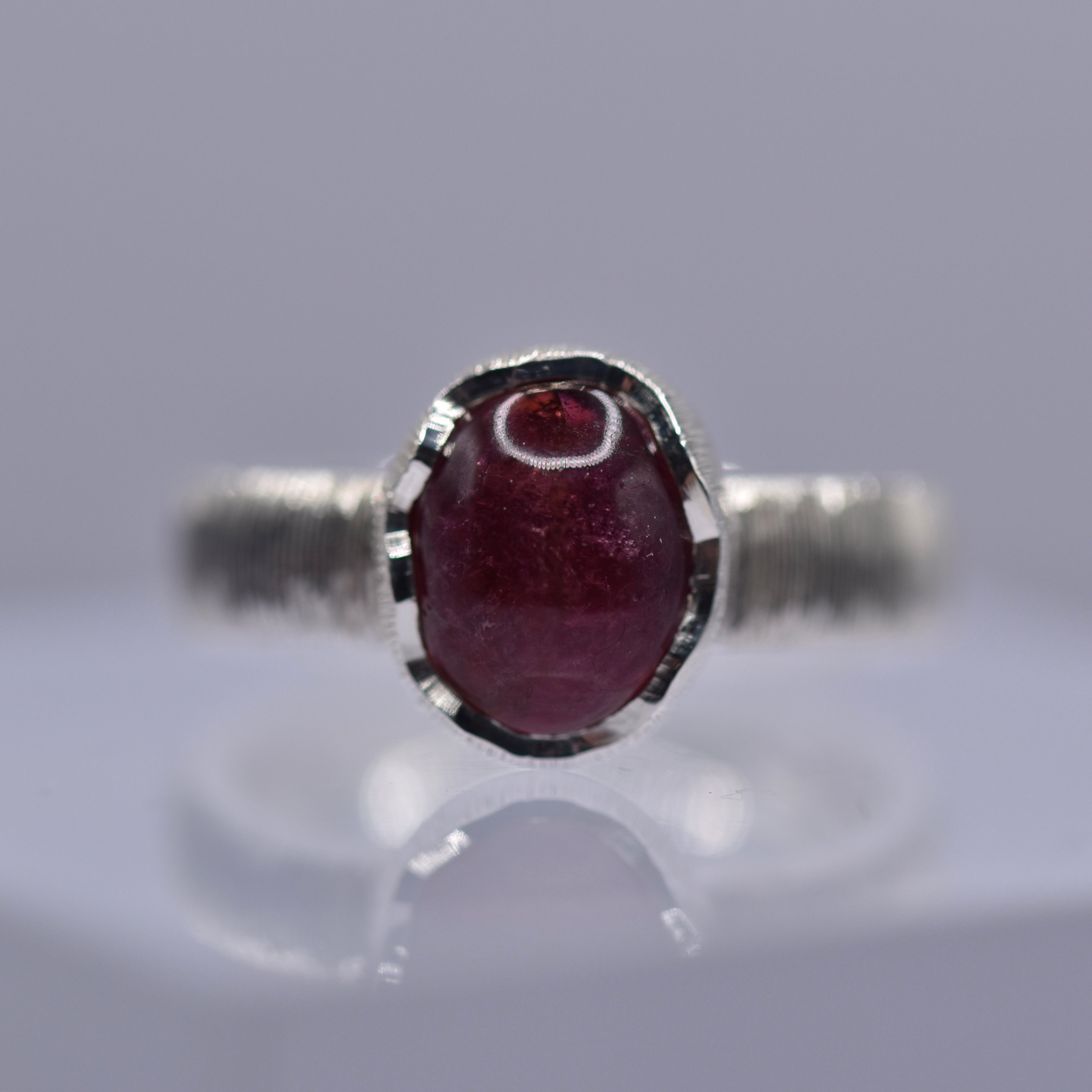 Silver ring with a wavy setting with a pink tourmaline stone in the centre