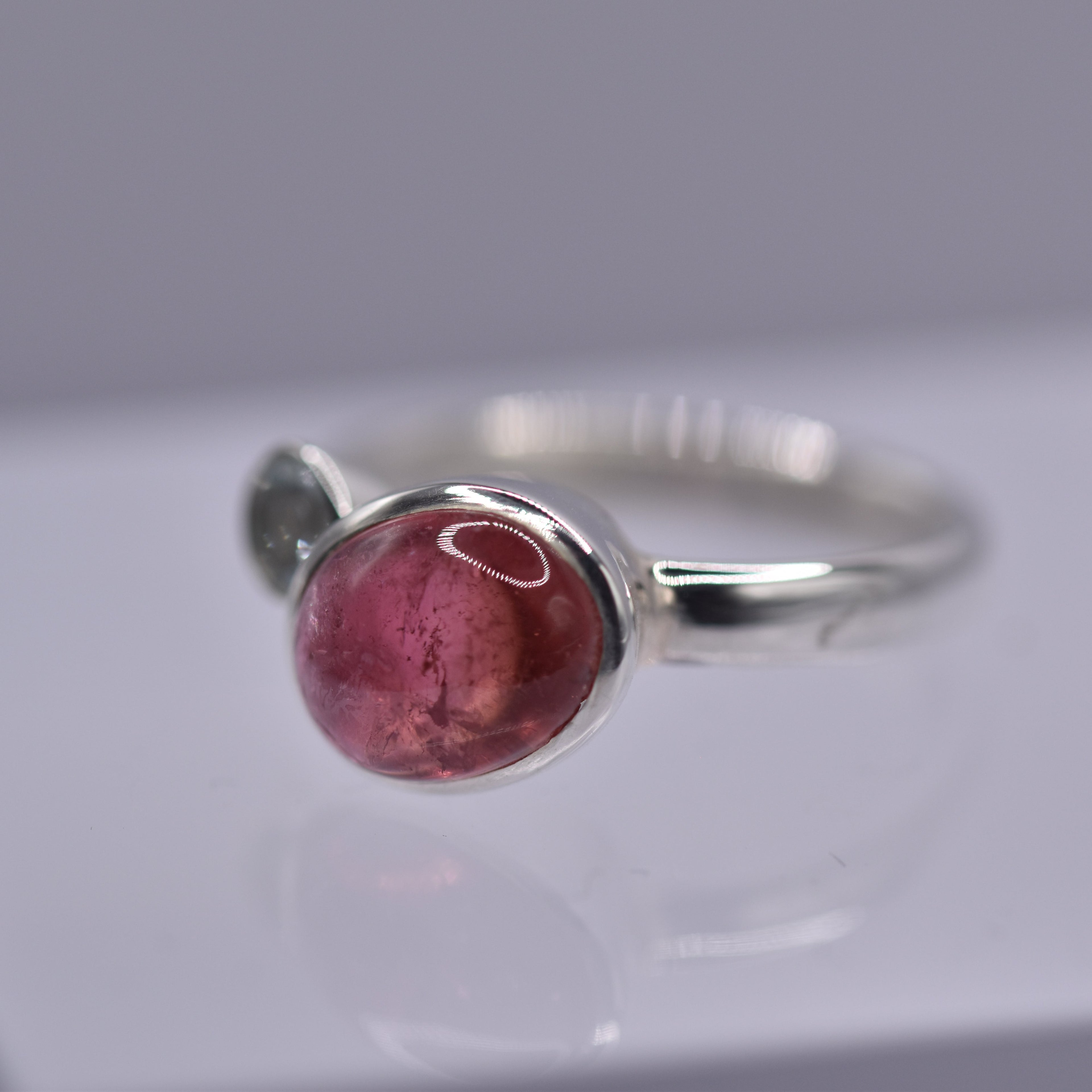 Silver ring with a pink stone on a gray background