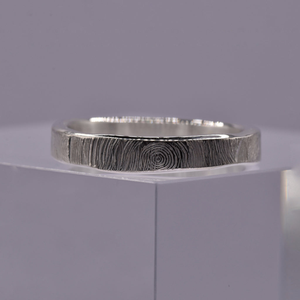 Silver ring with a textured circular pattern band on a gray background