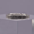 Silver ring with a textured circular pattern band on a gray background