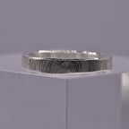 Silver ring with a textured circular pattern band on a gray background
