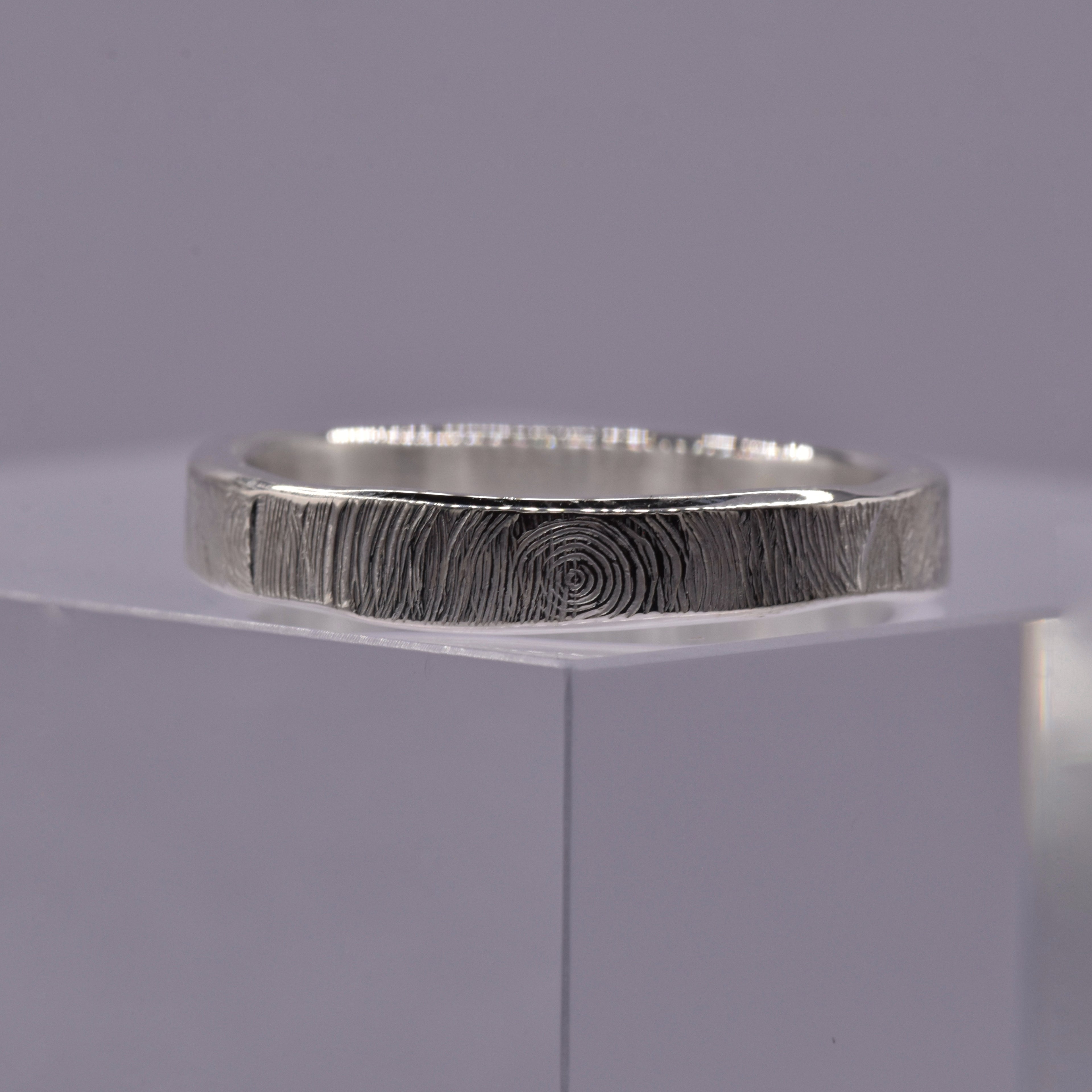Silver ring with a textured circular pattern band on a gray background