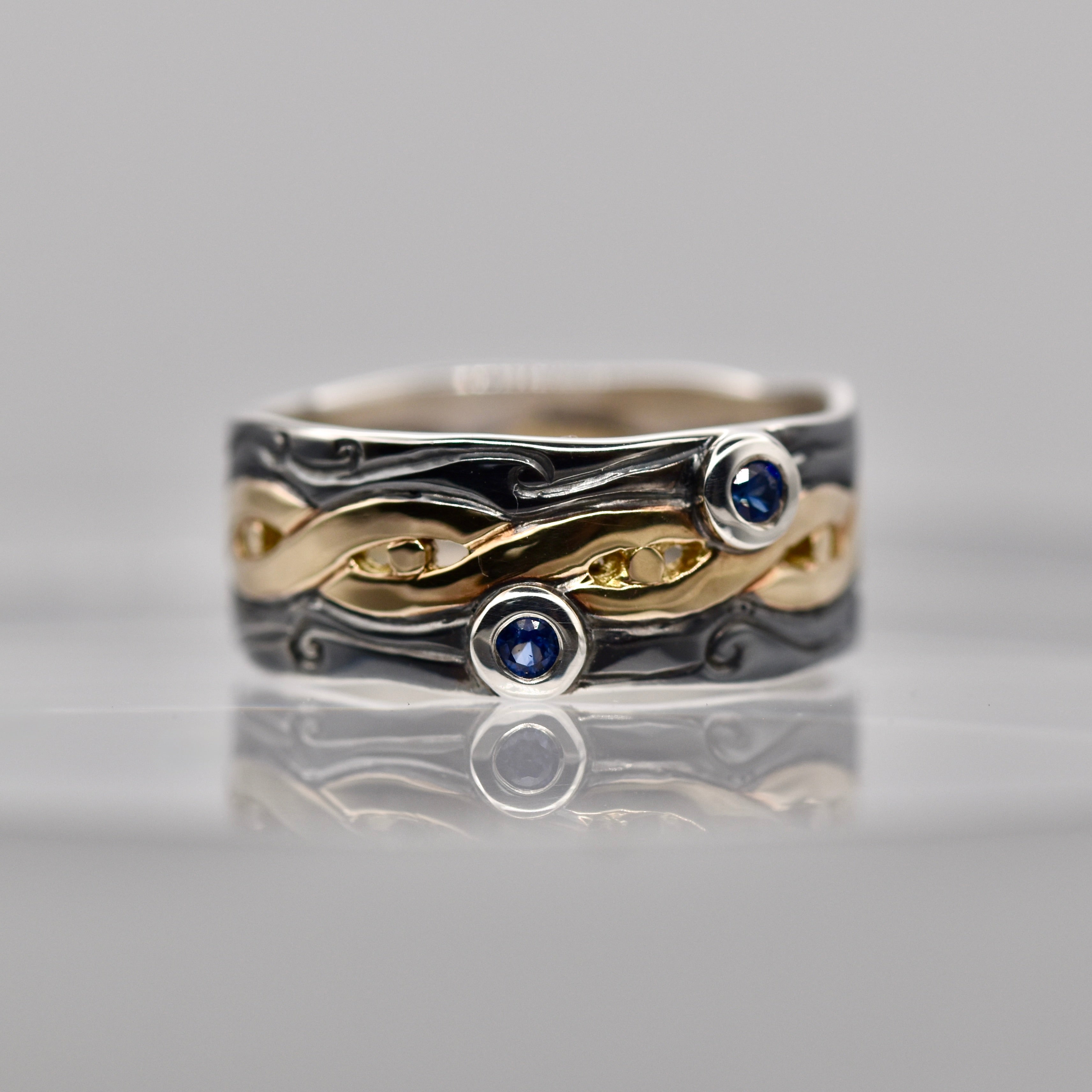Silver and gold ring with blue gemstones on a gray background