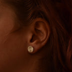 Close-up of an ear wearing a silver stud earring with a radiating design.