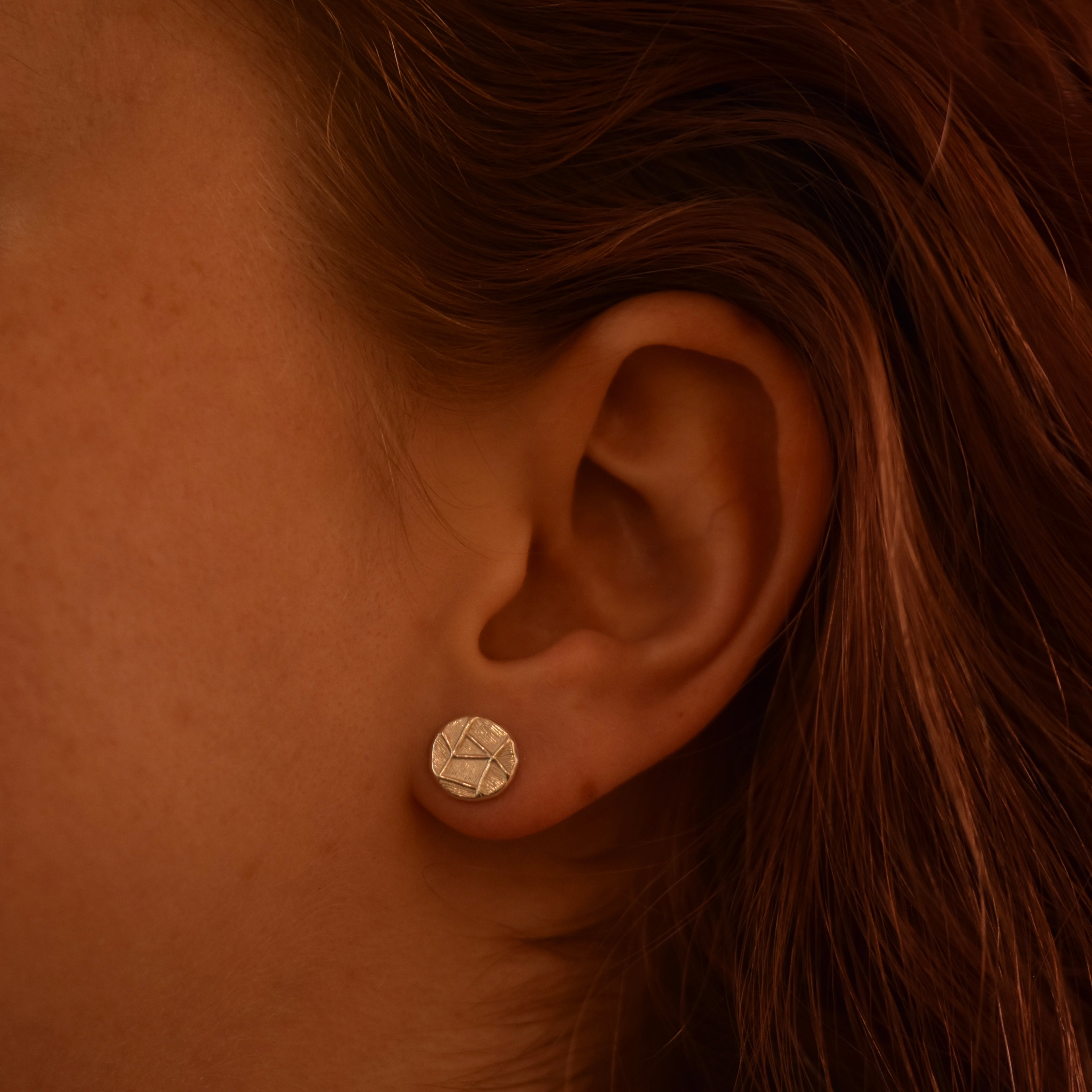 Close-up of an ear wearing a silver geometric earring