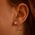 Close-up of an ear wearing a silver earring with geometric design.