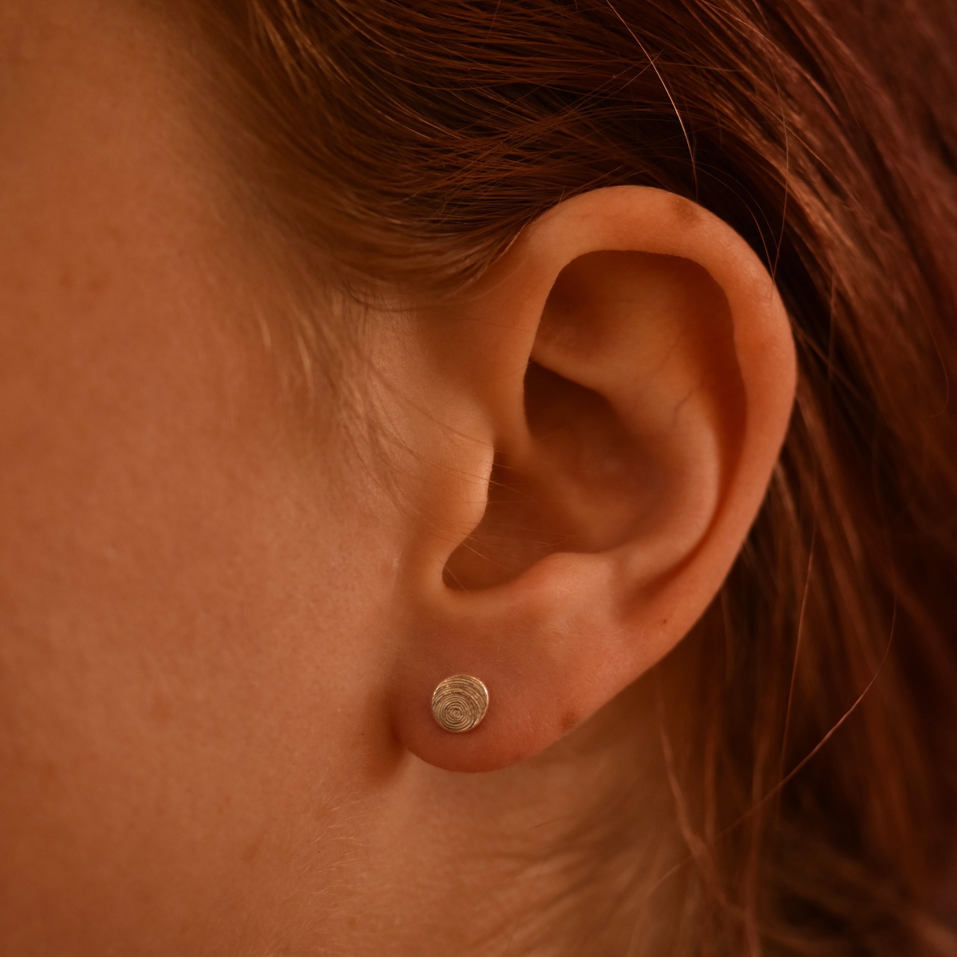 Close-up of an ear with a silver spiral earring 