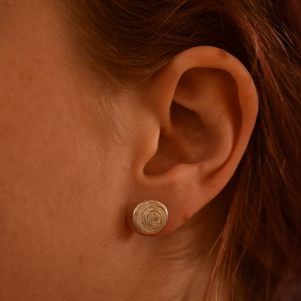 Close-up of an ear wearing a silver spiral earring.