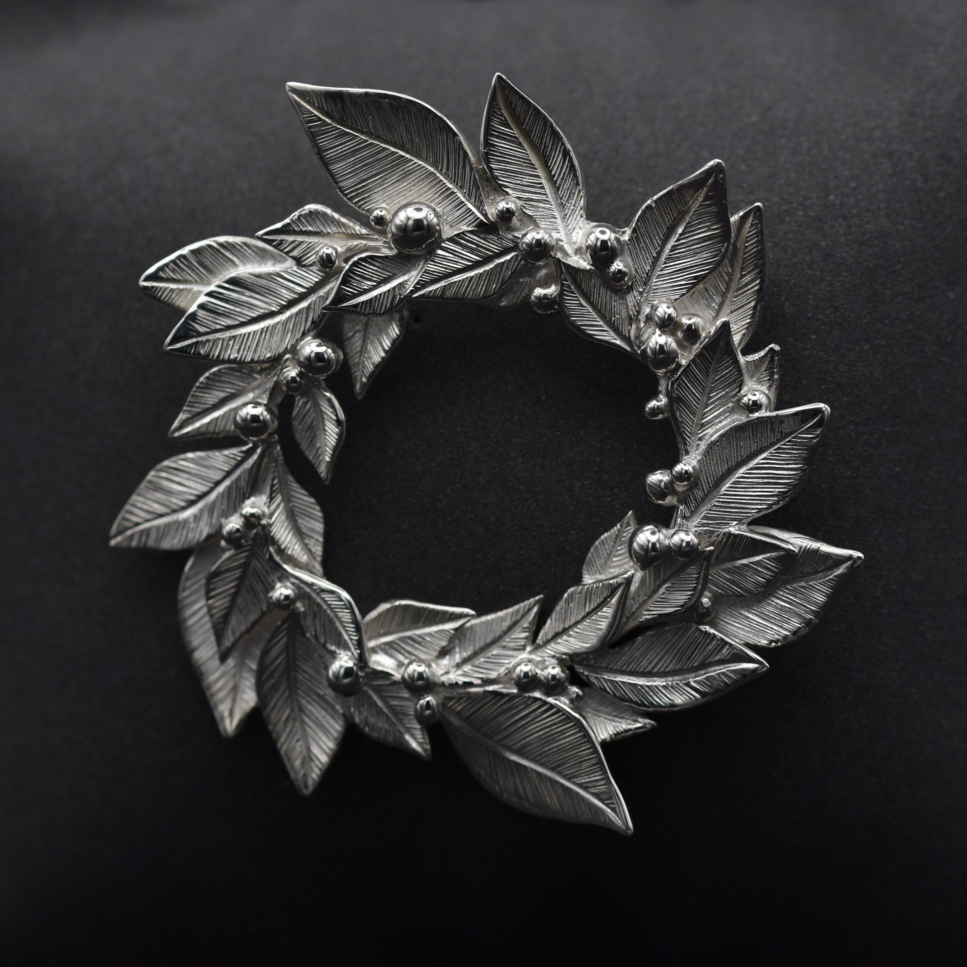 Silver leaf wreath brooch on a black background