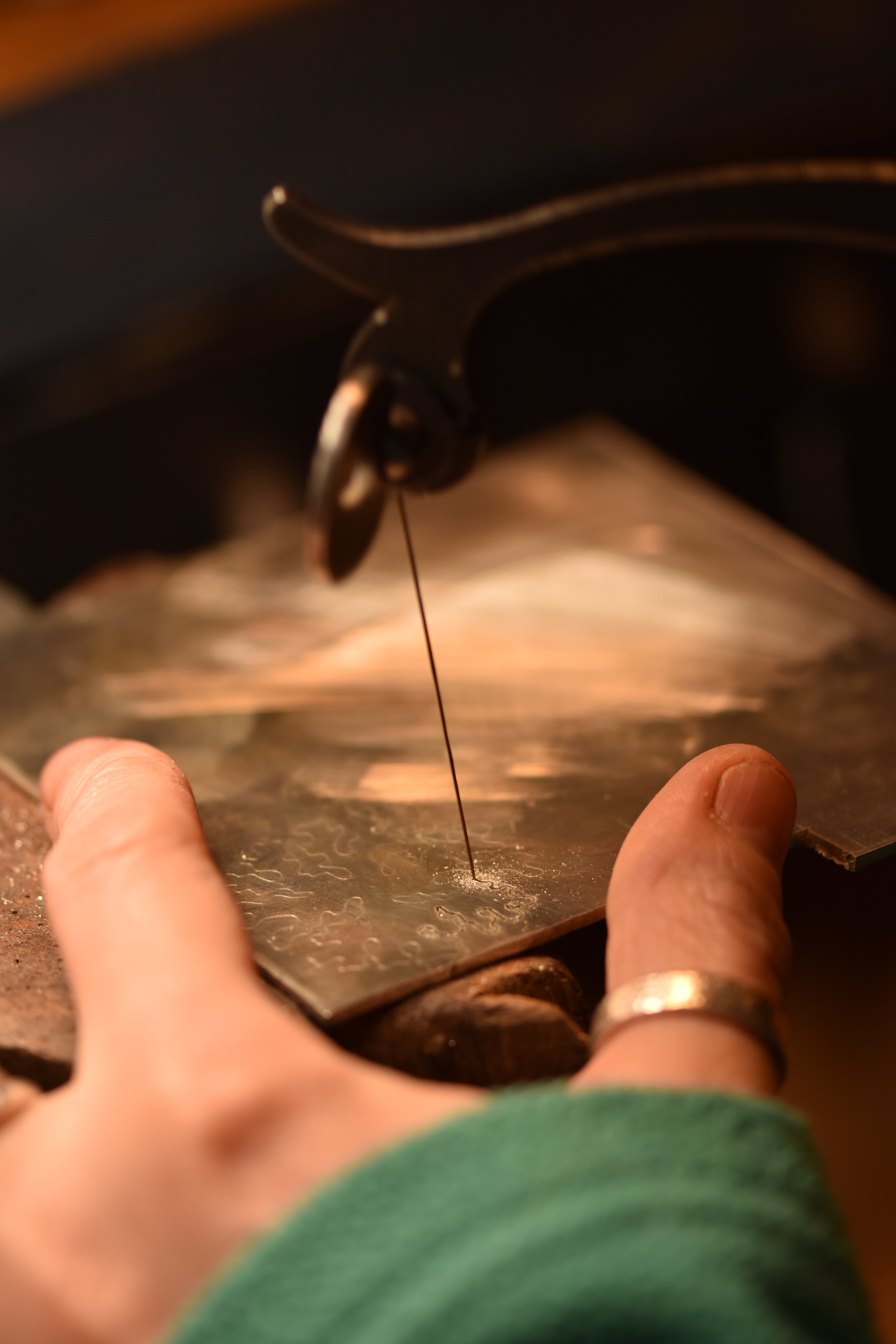 close up of hands hand piercing a silver design