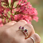 Silver ring with pink gemstones on a hand holding pink flowers