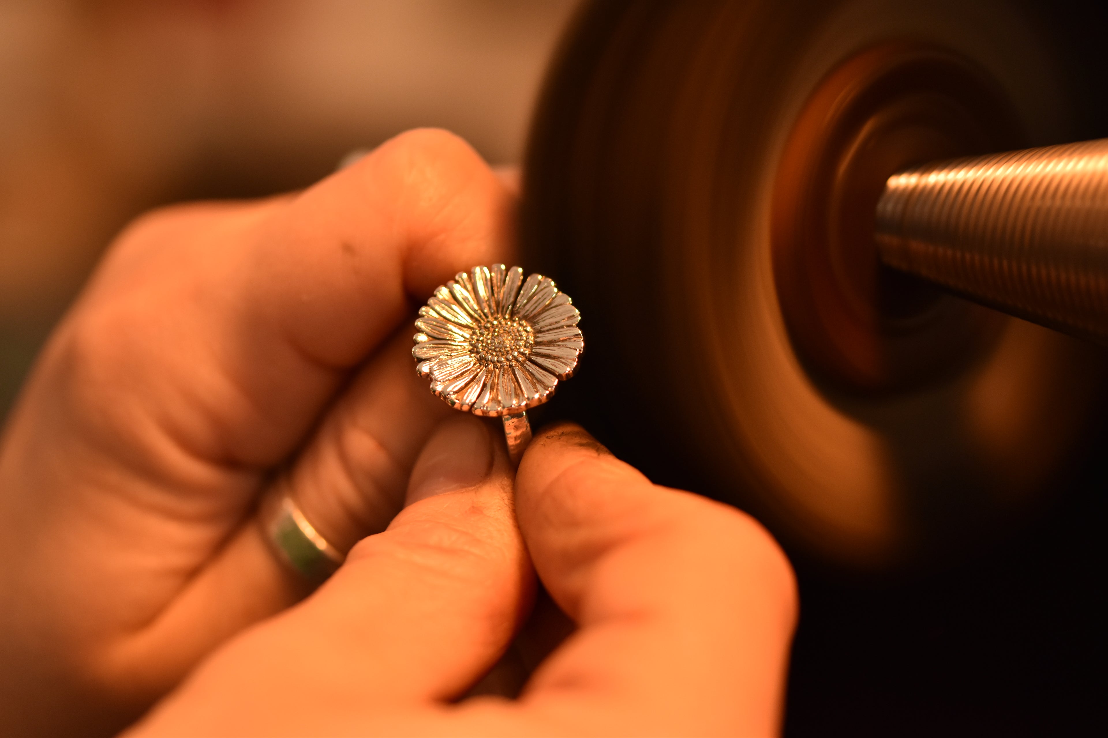 hands polishing a daisy ring on rotating polishing mop