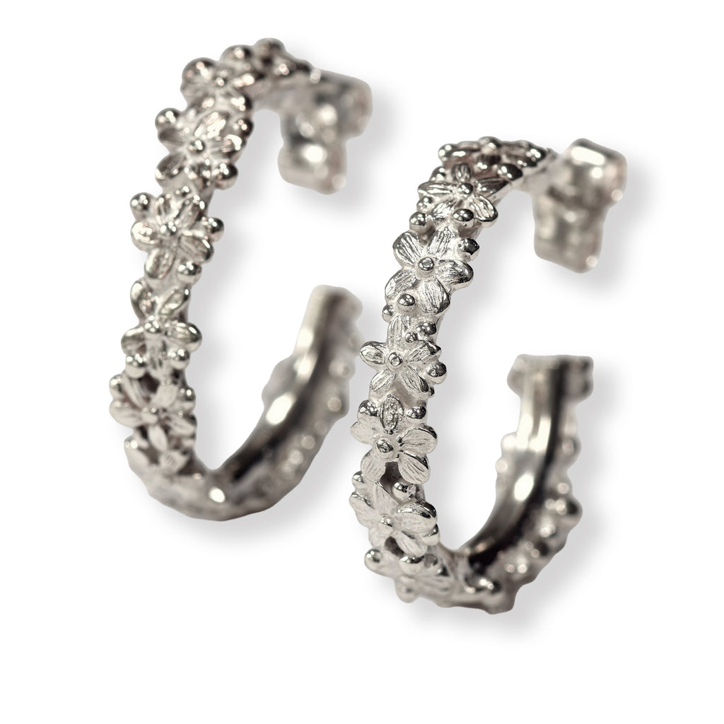 Pair of silver hoop earrings with floral designs on a white background