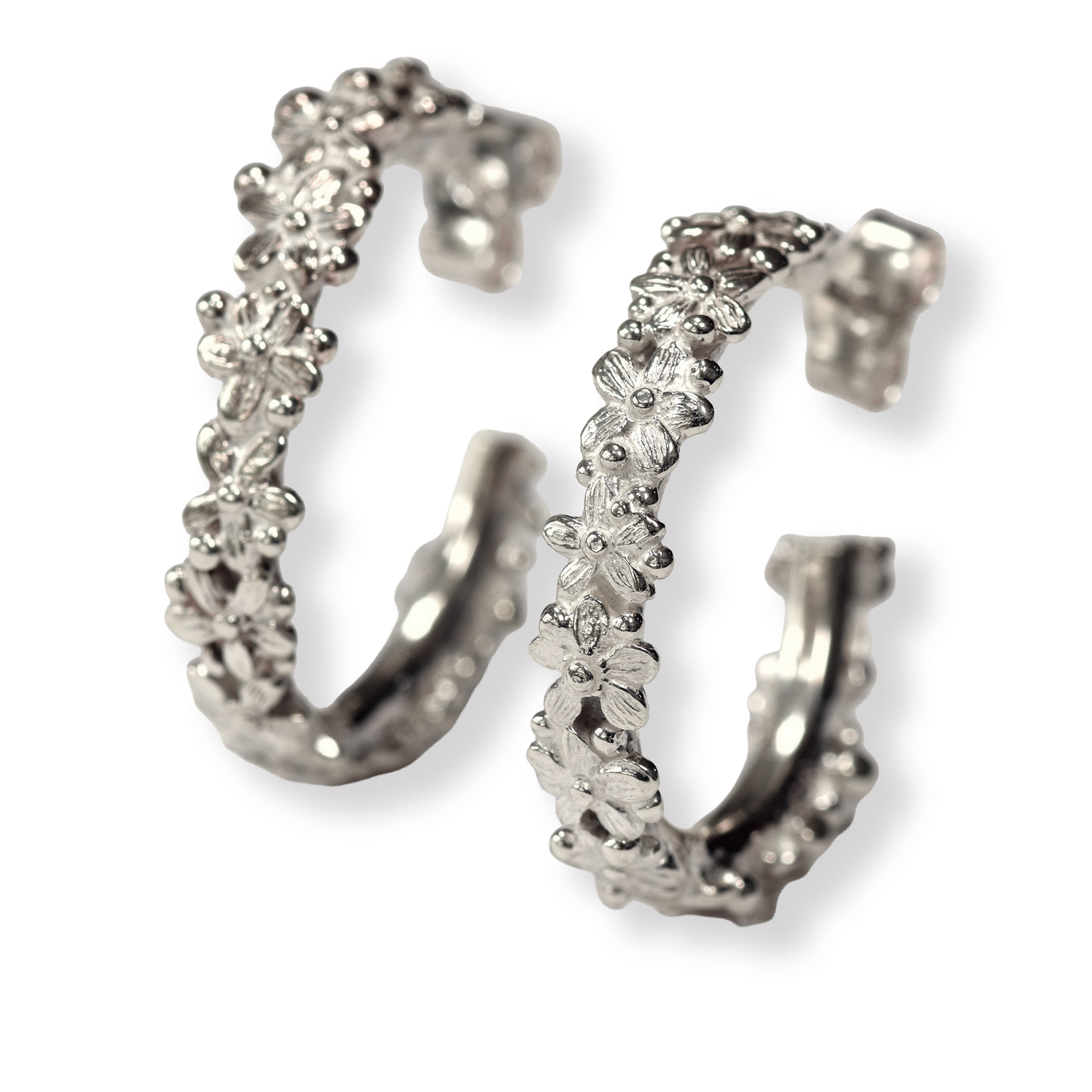 Pair of silver hoop earrings with floral designs on a white background