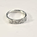 Silver ring with five flowers across the front on a light gray background