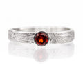 Silver ring with a red gemstone on a white background