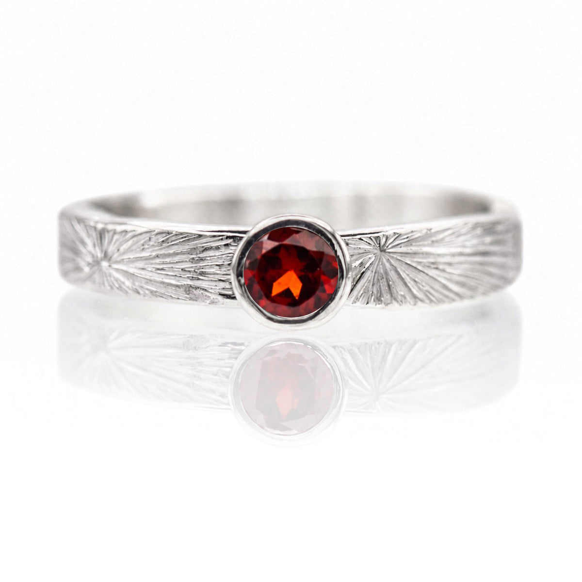 Silver ring with a red gemstone on a white background
