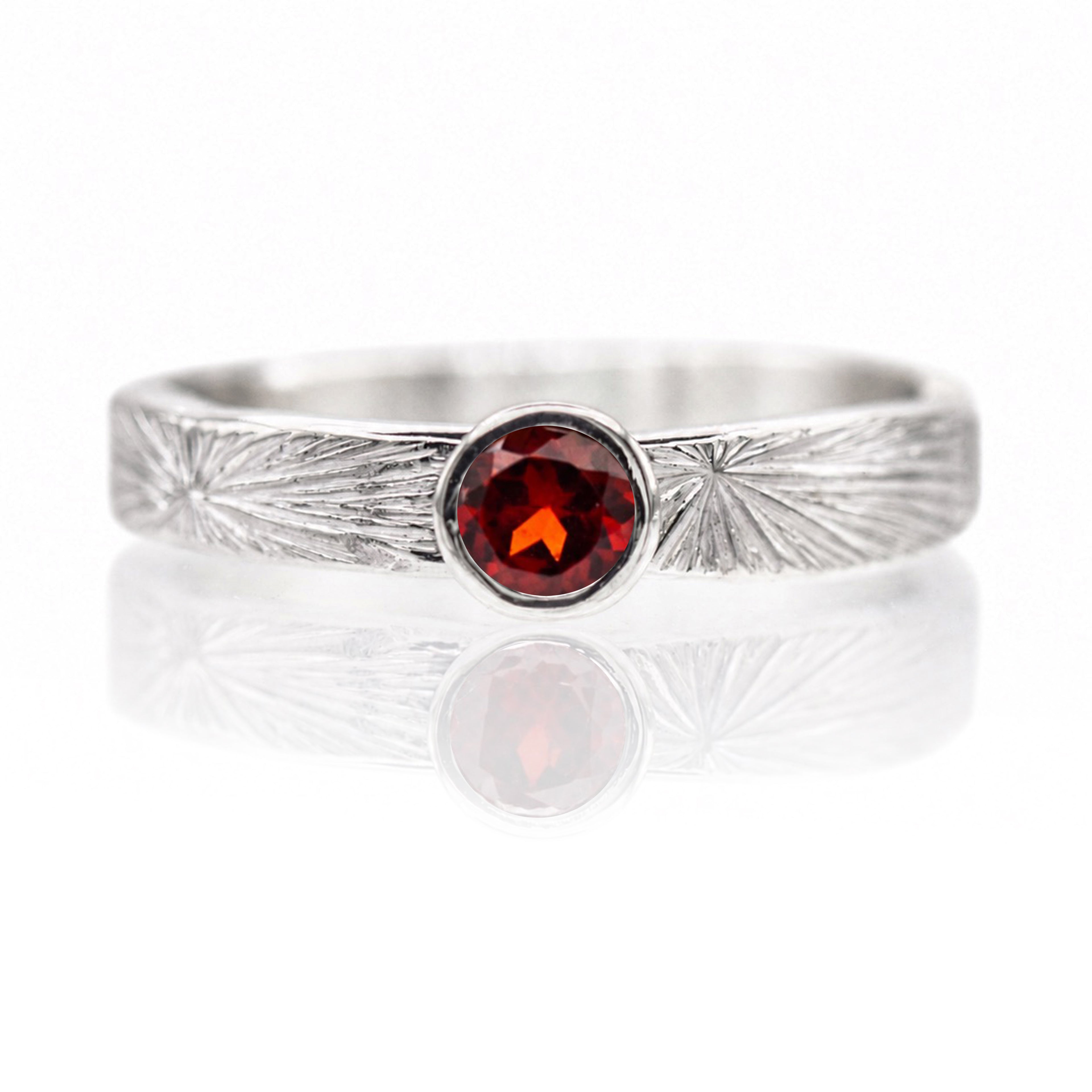 Silver ring with a red gemstone on a white background