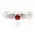 Silver ring with a red gemstone on a white background