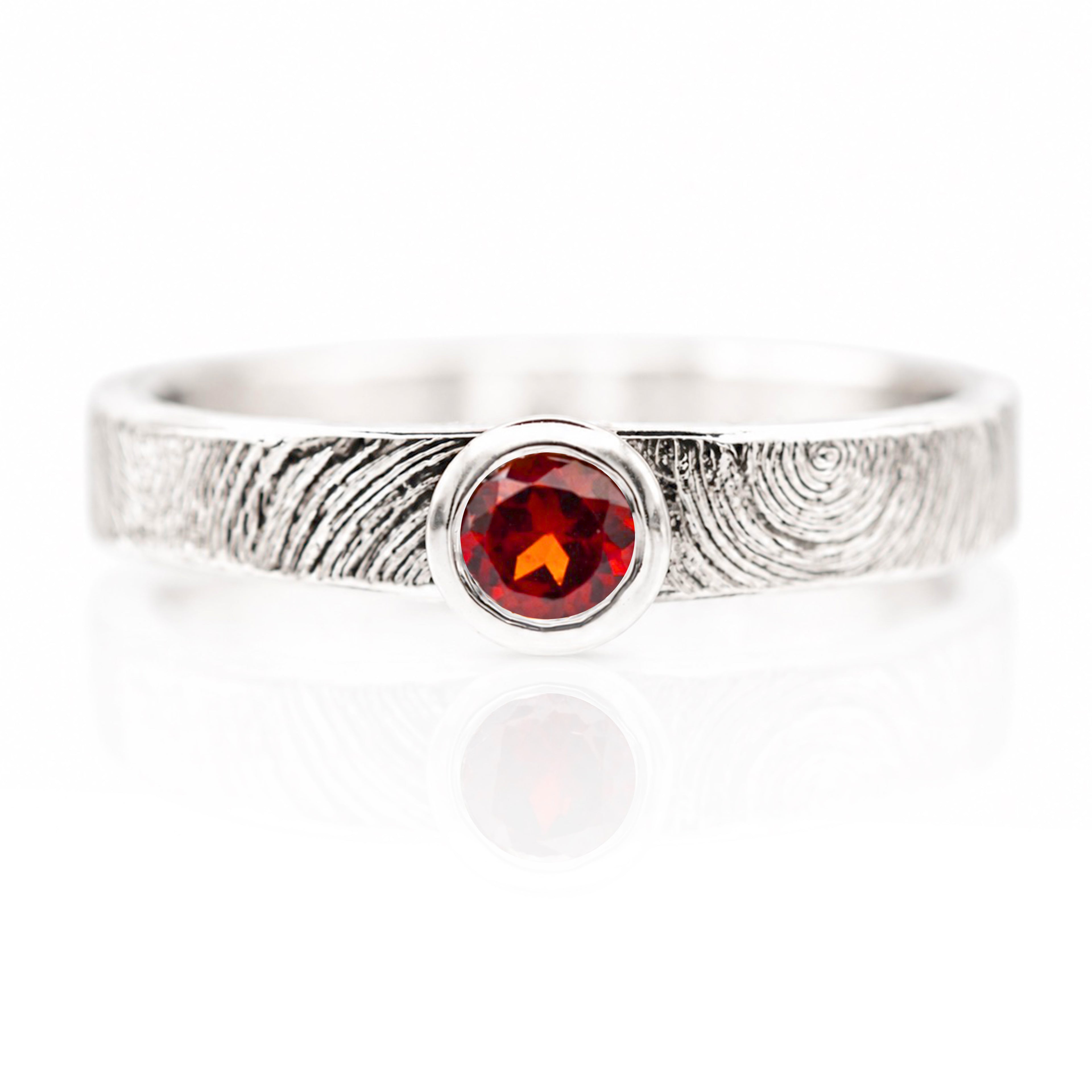 Silver ring with a red gemstone on a white background