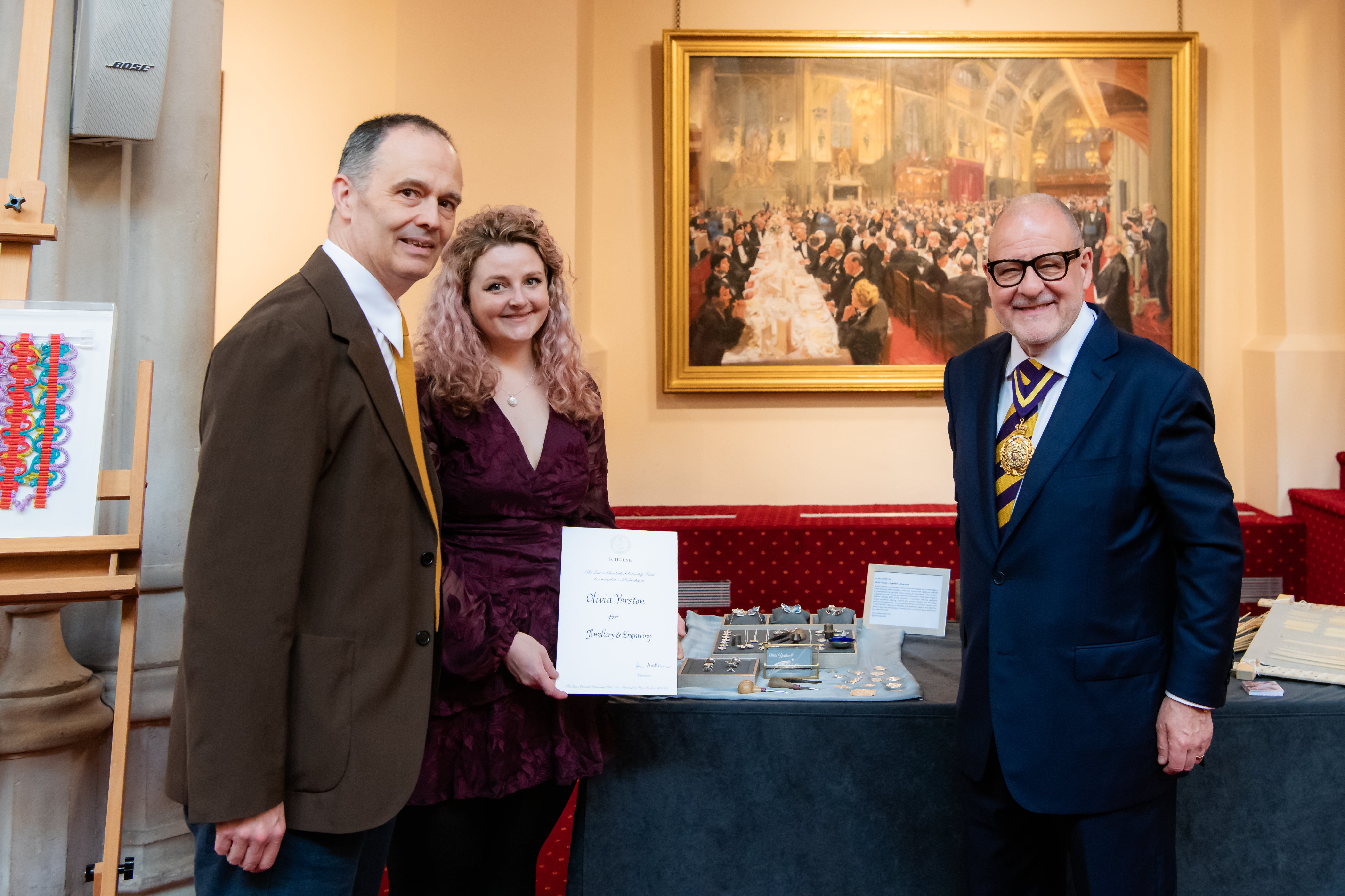 Woman receiving a certificate with 2 men presenting it 