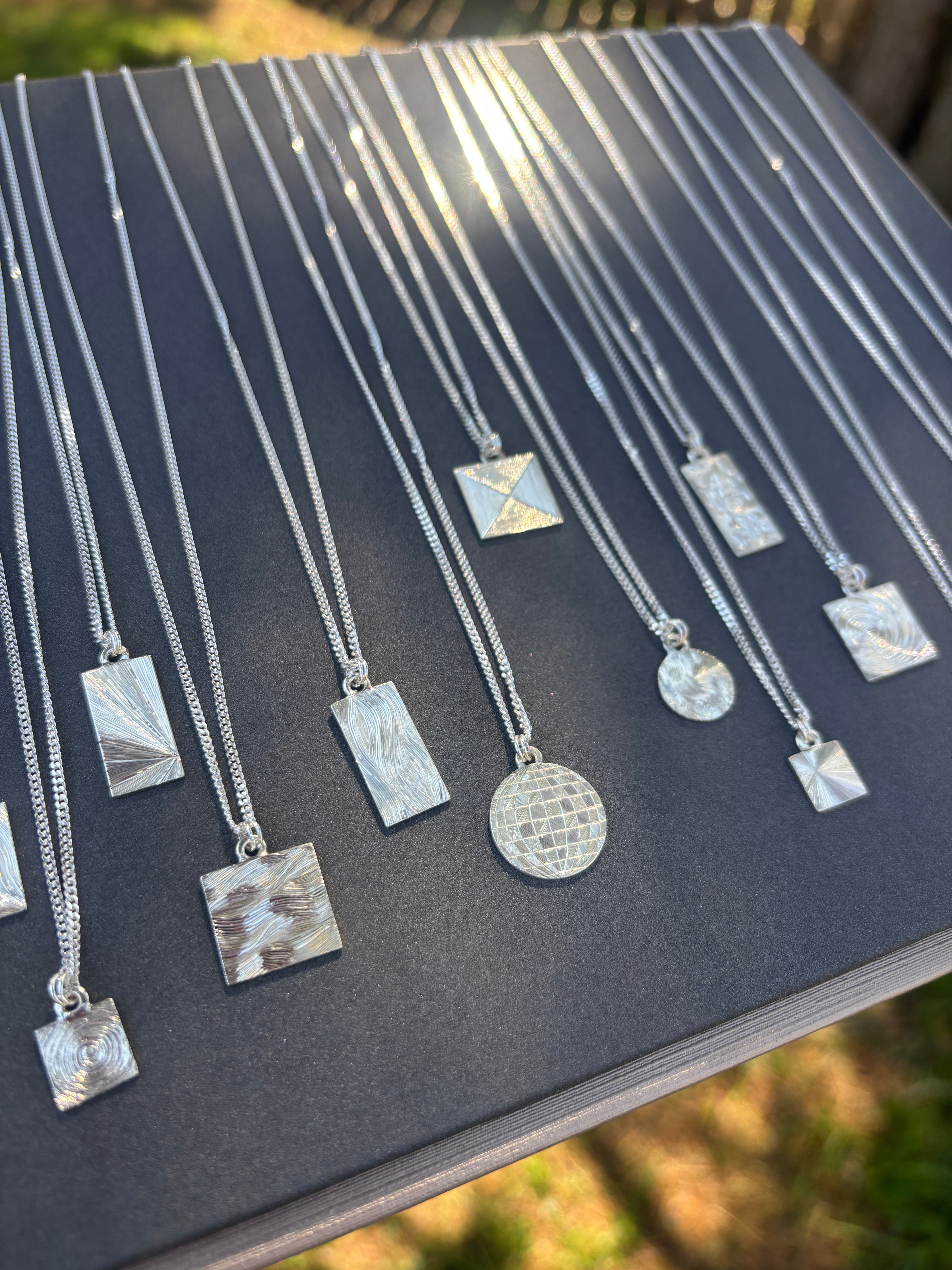 Silver necklaces with various pendants on a black surface