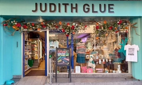 Storefront with 'Judith Glue' sign and colorful decorations