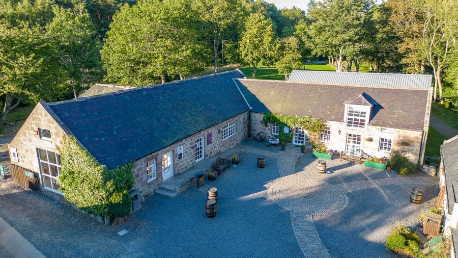 Aerial view of a large stone building with a courtyard surrounded by trees.
