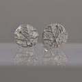 Pair of silver round earrings with frost design of frost pattern on a reflective surface.