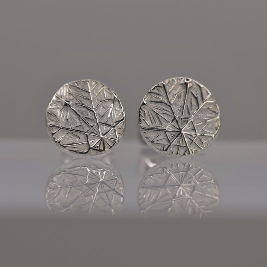 Pair of silver round earrings with textured design of frost pattern on a reflective surface.