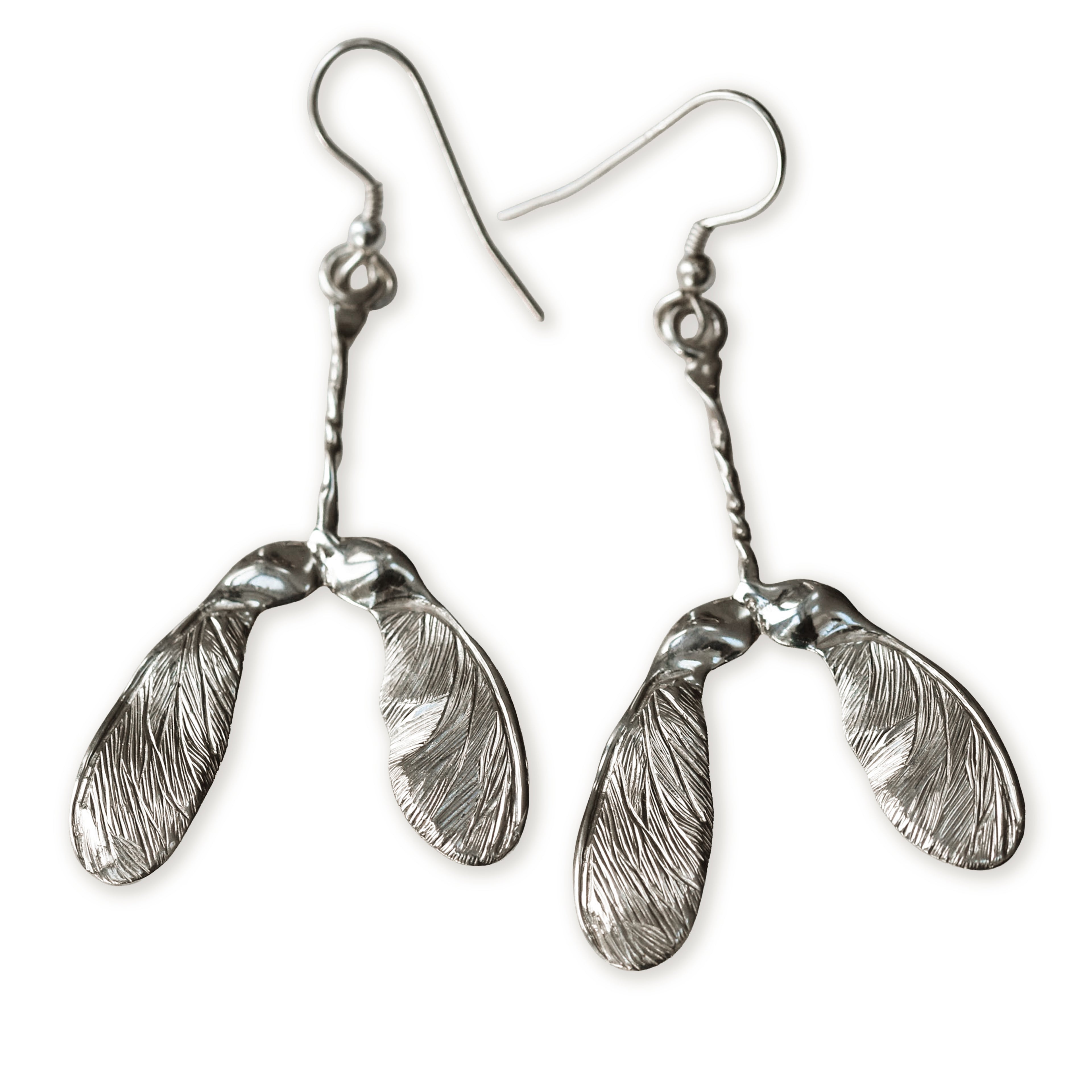 Silver sycamore seed earrings on a white background