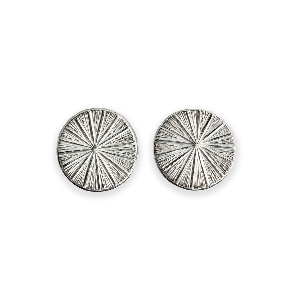 Pair of silver circular earrings with radiating design on a white background